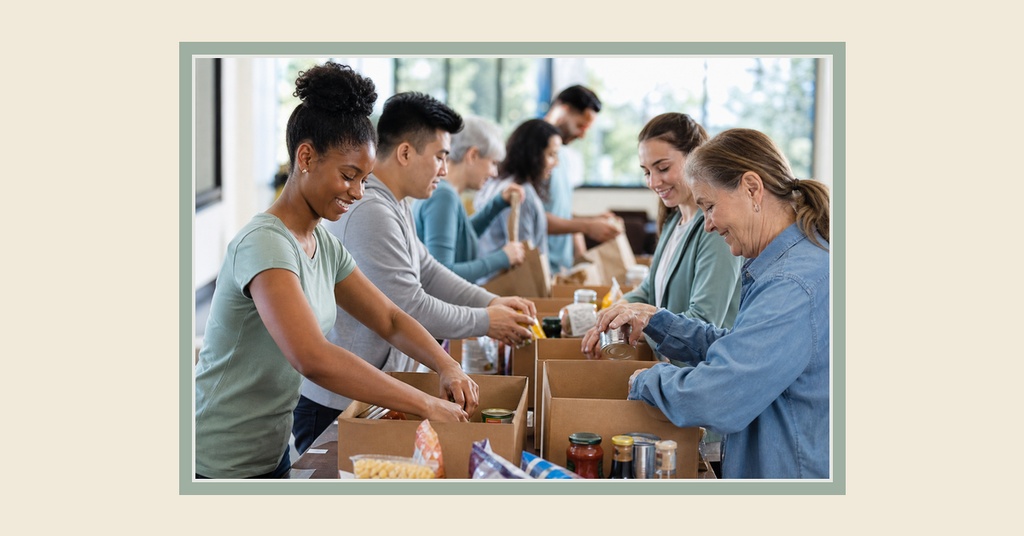 Volunteers packing donated food into cardboard boxes at a community food drive table.