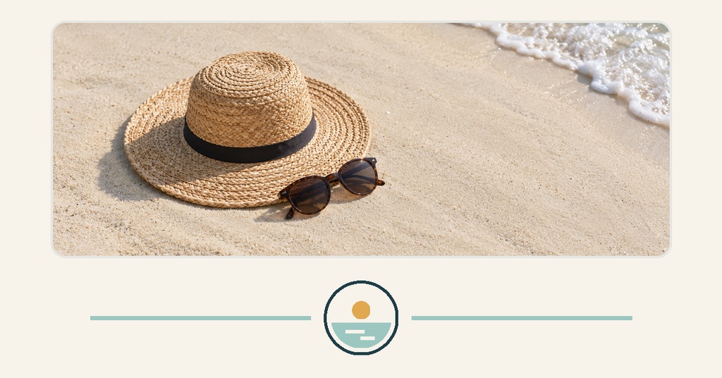 Straw sun hat and sunglasses on sandy beach with waves in the corner